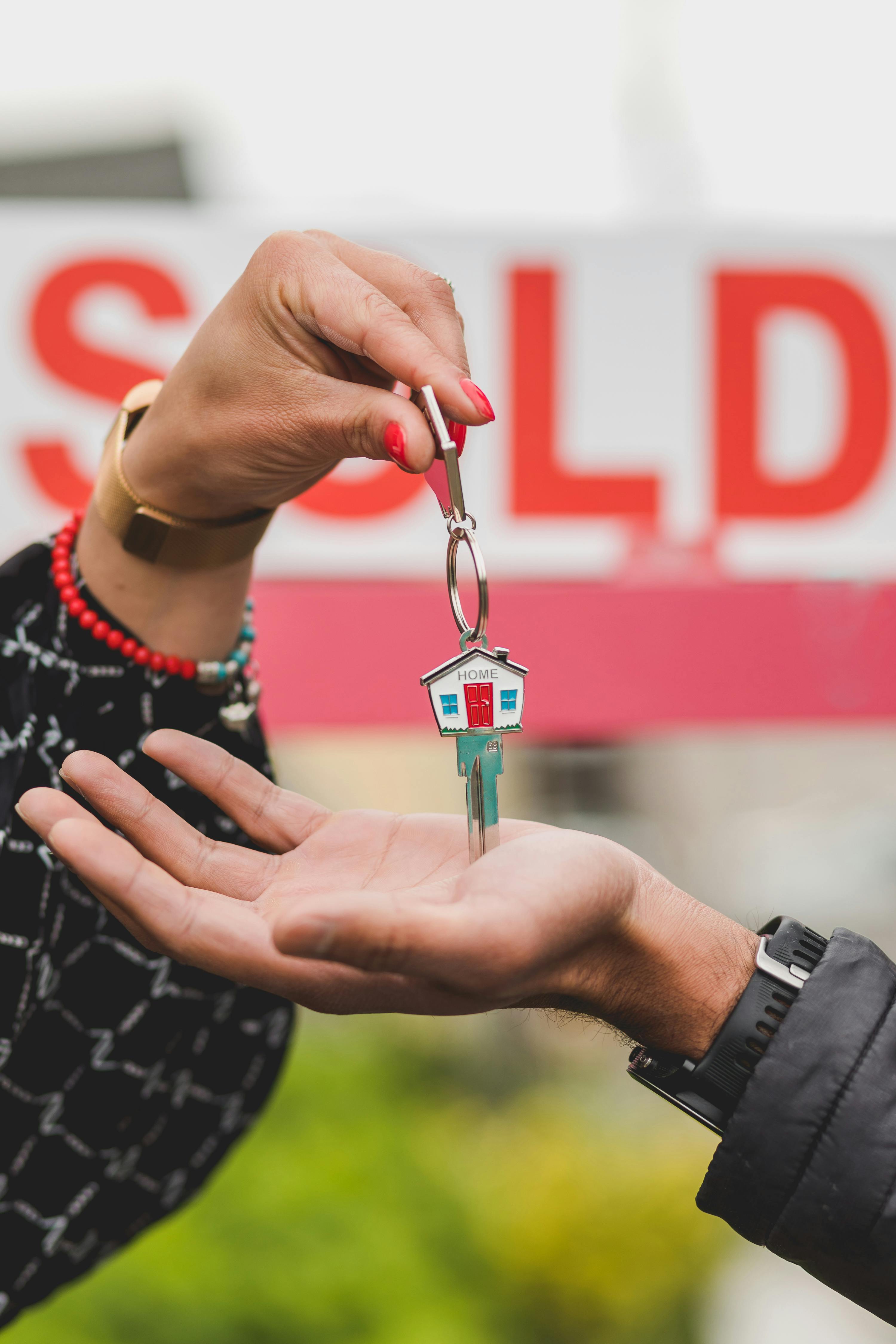 someone handing key to another person indicating  selling house